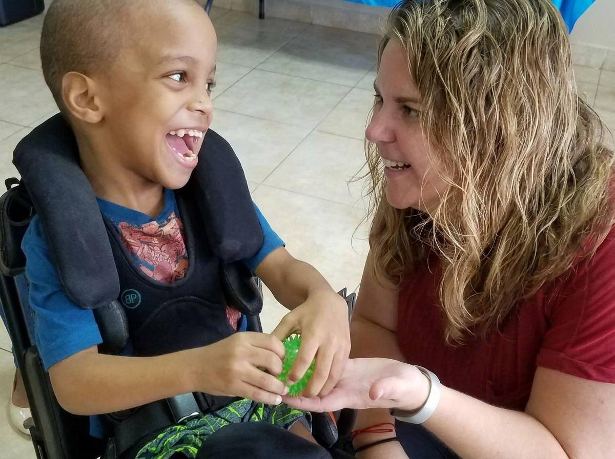 Angie sharing a joyful moment with a child in a wheelchair